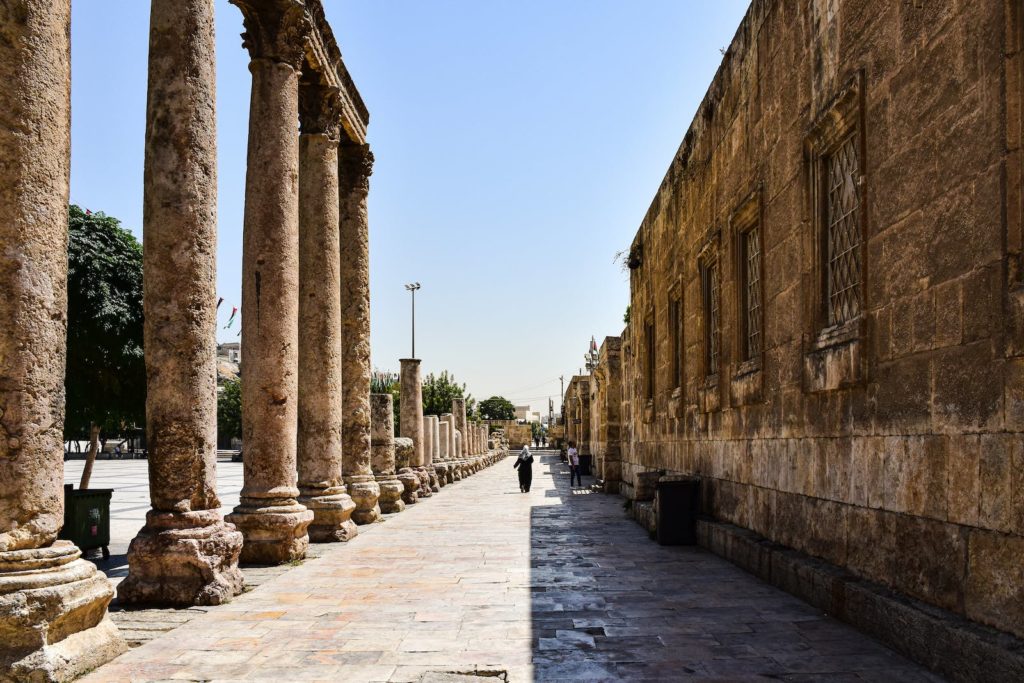 A narrow street with columns and a man walking